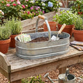 Contenedor ovalado de acero galvanizado para plantas con asa de madera